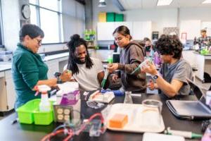 A group of four students doing science experiments and smiling